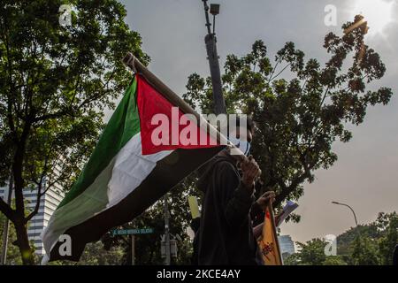 Un uomo che indossa la maschera porta bandiera palestinese a sostegno della Palestina durante il giorno internazionale al-Quds fuori dall'ambasciata degli Stati Uniti a Giacarta il 7 maggio 2021. Al-Quds Day che è stato dichiarato dal defunto leader spirituale iraniano Ayatollah Ruhollah Khomeini nel 1979 come giornata internazionale di lotta contro Israele e per la liberazione di Gerusalemme è osservato ogni ultimo Venerdì del mese santo musulmano di Ramadan. Il giorno è una mossa per esprimere sostegno al popolo palestinese e la sua resistenza contro l'occupazione israeliana. (Foto di Afriadi Hikmal/NurPhoto) Foto Stock