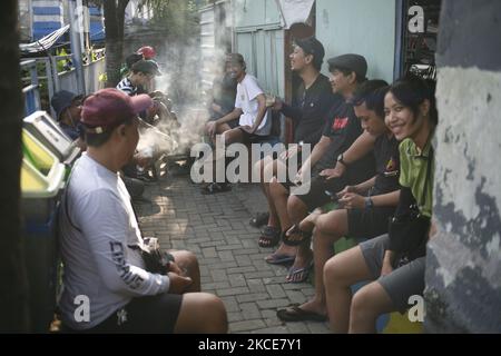 Gruppo asiatico di amici appeso fuori in caffè tradizionale o ristorante chiamato warung a Kediri, Eastjava, Indonesia. Foto Stock