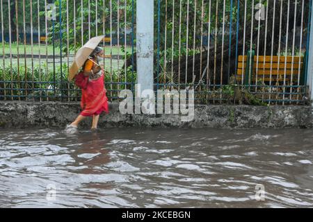Una signora cerca di fare la loro strada attraverso una strada allagata a Kolkata , in India , il 11 maggio 2021 . (Foto di Debarchan Chatterjee/NurPhoto) Foto Stock