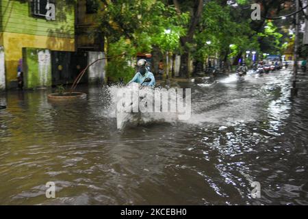 Un motociclista si fa strada su una strada allagata a Kolkata , in India , il 11 maggio 2021 . (Foto di Debarchan Chatterjee/NurPhoto) Foto Stock