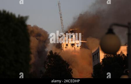 Fumo e fiamme si innalzano da un edificio a torre che viene distrutto da attacchi aerei israeliani in mezzo a un flare di violenza israelo-palestinese, a Gaza City 12 maggio 2021. (Foto di Majdi Fathi/NurPhoto) Foto Stock