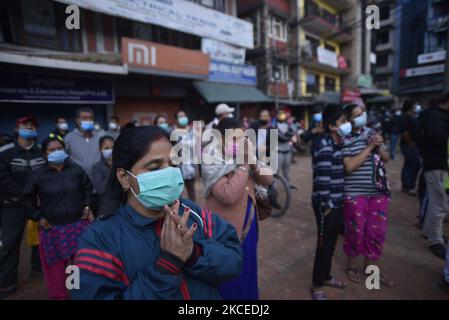 I devoti nepalesi insieme con la maschera facciale offrono rituali dopo che i sacerdoti portano Rato Machindranath verso il carro il primo giorno del festival più lungo del carro del Nepal durante il blocco proibitivo della pandemia di covid a Lalitpur, Nepal il mercoledì 12 maggio 2021. Rato Machindranath è anche detto come il "Dio della pioggia" e sia indù e buddisti adorano il Machindranath nella speranza di una buona pioggia per prevenire la siccità durante la stagione delle piantagioni di riso. (Foto di Narayan Maharjan/NurPhoto) Foto Stock