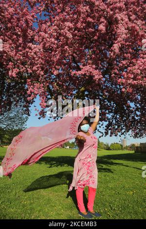 Donna che indossa una maschera facciale per proteggerla dal nuovo coronavirus (COVID-19) posa da un albero di ananas coperto di fiori rosa durante la stagione primaverile a Toronto, Ontario, Canada il 14 maggio 2021. (Foto di Creative Touch Imaging Ltd./NurPhoto) Foto Stock