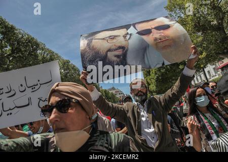 Un manifestante solleva un poster con un ritratto fotografico del presidente siriano Bachar al-Assad e del leader di Hezbollah Hassan Nasrallah durante una manifestazione tenuta da migliaia di manifestanti tunisini e palestinesi su Avenue Habib Bourguiba, nella capitale Tunisi, in Tunisia, il 15 maggio 2021; A sostegno del popolo palestinese e per protestare contro gli attacchi aerei di Israele sulla striscia di Gaza e contro le violazioni israeliane nei territori occupati in Palestina, in particolare nel quartiere palestinese di Gerusalemme est, lo sceicco Jarrah. (Foto di Chardy ben Ibrahim/NurPhoto) Foto Stock