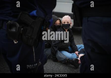 Weronika (20, L) e Lu (21, R) bloccano un furgone a Varsavia, Polonia il 19 maggio 2021. Gli attivisti anti-aborto in un furgone che mostra immagini grafiche di feti abortiti sono stati fermati da attivisti pro-scelta nel centro di Varsavia, Polonia. L'attivista Weronika, ventenne, si è seduto sulla strada di fronte all'autobus, in quanto si trovava all'uscita della trafficata rotonda ONZ. Gli autisti dell’autobus suonavano un forte allarme attraverso gli altoparlanti del furgone nel tentativo di scongiurare l’attivista. Altre due donne, Magda e Lu, si accovacciarono sotto l'autobus. Diverse dozzine di poliziotti arrivarono presto sulla scena e gli attivisti furono dati f Foto Stock