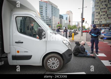 Weronika (20, L) e Lu (21, R) bloccano un furgone a Varsavia, Polonia il 19 maggio 2021. Gli attivisti anti-aborto in un furgone che mostra immagini grafiche di feti abortiti sono stati fermati da attivisti pro-scelta nel centro di Varsavia, Polonia. L'attivista Weronika, ventenne, si è seduto sulla strada di fronte all'autobus, in quanto si trovava all'uscita della trafficata rotonda ONZ. Gli autisti dell’autobus suonavano un forte allarme attraverso gli altoparlanti del furgone nel tentativo di scongiurare l’attivista. Altre due donne, Magda e Lu, si accovacciarono sotto l'autobus. Diverse dozzine di poliziotti arrivarono presto sulla scena e gli attivisti furono dati f Foto Stock