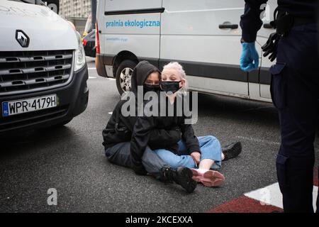 Weronika (20, L) e Lu (21, R) bloccano un furgone a Varsavia, Polonia il 19 maggio 2021. Gli attivisti anti-aborto in un furgone che mostra immagini grafiche di feti abortiti sono stati fermati da attivisti pro-scelta nel centro di Varsavia, Polonia. L'attivista Weronika, ventenne, si è seduto sulla strada di fronte all'autobus, in quanto si trovava all'uscita della trafficata rotonda ONZ. Gli autisti dell’autobus suonavano un forte allarme attraverso gli altoparlanti del furgone nel tentativo di scongiurare l’attivista. Altre due donne, Magda e Lu, si accovacciarono sotto l'autobus. Diverse dozzine di poliziotti arrivarono presto sulla scena e gli attivisti furono dati f Foto Stock