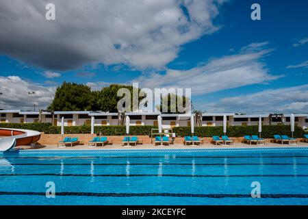 La piscina con ombrelloni e lettini pronti all'uso presso il Beach club Nettuno di Molfetta (Italia) il 20 maggio 2021. Le spiagge balneari e le piscine in Puglia sono già state al lavoro per diverse settimane per la riapertura e sono pronte per la prenotazione. Le stesse procedure seguiranno lo scorso anno con protocolli creati ad hoc per contenere il più possibile la diffusione e poter vivere nonostante il virus, sperando in una stagione il più possibile pacifica. Le regole principali da rispettare per i bagnanti e i proprietari delle spiagge e delle piscine sono: Ad almeno un metro di distanza nelle aree comuni, quindi, Foto Stock