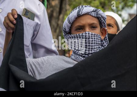 Un bambino porta una bandiera palestinese mentre partecipa ad un'azione di solidarietà a Palu, nella Provincia Centrale di Sulawesi, Indonesia, il 21 maggio 2021. L'azione di solidarietà seguita da membri dell'organizzazione musulmana è una forma di sostegno e di difesa per i palestinesi per gli attacchi e le atrocità sioniste israeliane. Gaza sta causando la crisi umanitaria nella regione. (Foto di Basri Marzuki/NurPhoto) Foto Stock