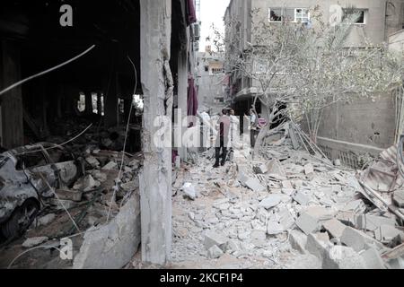 Le persone ispezionano un buco e le macerie di un edificio residenziale distrutto che è stato colpito da attacchi aerei israeliani, a Gaza City, giovedì 20 maggio 2021.(Photo by Momen Faiz/NurPhoto) Foto Stock