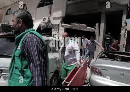 Le persone ispezionano un buco e le macerie di un edificio residenziale distrutto che è stato colpito da attacchi aerei israeliani, a Gaza City, giovedì 20 maggio 2021.(Photo by Momen Faiz/NurPhoto) Foto Stock