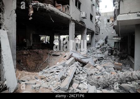 Le persone ispezionano un buco e le macerie di un edificio residenziale distrutto che è stato colpito da attacchi aerei israeliani, a Gaza City, giovedì 20 maggio 2021.(Photo by Momen Faiz/NurPhoto) Foto Stock