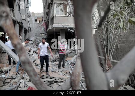 Le persone ispezionano un buco e le macerie di un edificio residenziale distrutto che è stato colpito da attacchi aerei israeliani, a Gaza City, giovedì 20 maggio 2021.(Photo by Momen Faiz/NurPhoto) Foto Stock