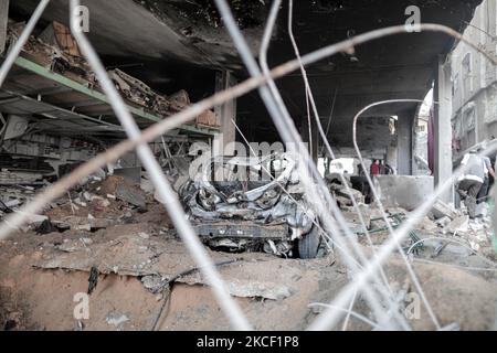 Le persone ispezionano un buco e le macerie di un edificio residenziale distrutto che è stato colpito da attacchi aerei israeliani, a Gaza City, giovedì 20 maggio 2021.(Photo by Momen Faiz/NurPhoto) Foto Stock