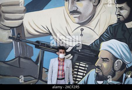 Un uomo iraniano che indossa una maschera protettiva guarda mentre si trova di fronte a un murale durante un raduno nella piazza Palestine nel centro di Teheran, il 22 maggio 2021. Un gruppo di uomini e donne iraniani si sono riuniti in piazza Palestina per celebrare la vittoria dei palestinesi su Israele, secondo la dichiarazione letta da un manifestante. (Foto di Morteza Nikoubazl/NurPhoto) Foto Stock