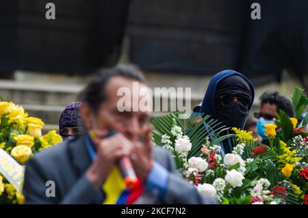 Un dimostratore che nasconde la sua identità con un cappuccio e occhiali guarda la protesta dietro le corone funebri mentre la gente si riunisce a Plaza de Bolivar di fronte al Campidoglio del Congresso per sostenere la mozione di censura al ministro della Difesa della Colombia Diego Molano dopo almeno 45 morti in casi di brutalità della polizia durante Le proteste contro il governo contro le riforme fiscali e sanitarie e la brutalità della polizia si sono evolute in Colombia nelle ultime settimane, a Bogotà, in Colombia, il 24 maggio 2021. (Foto di Sebastian Barros/NurPhoto) Foto Stock