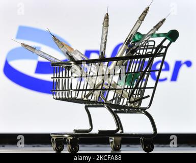 Le siringhe mediche nel mini carrello sono visibili davanti al logo Pfizer visualizzato su uno schermo. Venerdì 28 maggio 2021 a Dublino, Irlanda. (Foto di Artur Widak/NurPhoto) Foto Stock