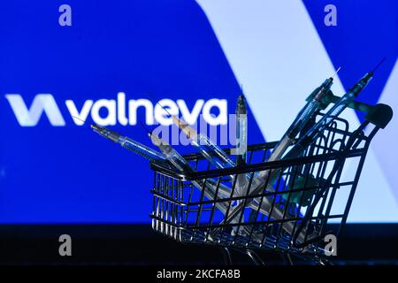 Le siringhe mediche nel mini carrello sono visibili davanti al logo Valneva visualizzato su uno schermo. Venerdì 28 maggio 2021 a Dublino, Irlanda. (Foto di Artur Widak/NurPhoto) Foto Stock