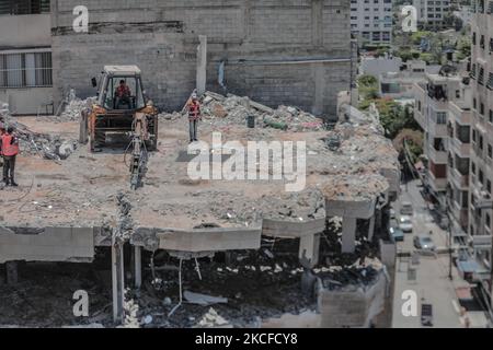 Le attrezzature pesanti da costruzione vengono utilizzate per demolire un edificio distrutto durante gli attacchi aerei israeliani della scorsa settimana a Gaza City. Israele e il movimento islamico palestinese Hamas hanno finora mantenuto un cessate il fuoco concordato che è andato il 21 maggio venerdì dopo 11 giorni di scontri mortali.(Foto di Momen Faiz/NurPhoto) Foto Stock