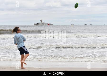 Dopo che l'intero fine settimana degli spettacoli sono stati cancellati a causa di forti tempeste, un'improvvisata mostra aerea del Memorial Day si è tenuta a New York's Jones Beach, con aerei della guerra mondiale 2 provenienti dall'American Airpower Museum e dagli U.S. Air Force Thunderbirds. Qui, un ragazzo gioca a calcio sulla spiaggia di fronte alla taglierina della Guardia Costiera Bruckenthal il 31 maggio 2021 a New York, Stati Uniti. (Foto di B.A. Van Sise/NurPhoto) Foto Stock