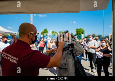 Un volontario misura la temperatura delle persone al di fuori del centro di vaccinazione prima di assumere la prima dose di vaccino il giorno aperto agli over 40s a Terlizzi, Italia, il 1 giugno 2021. A partire dal 1 giugno, i cittadini che hanno già una riserva e intendono anticipare la vaccinazione e quelli che non hanno ancora aderito alla campagna di vaccinazione hanno avuto la possibilità di accedere al banco senza la necessità di una prenotazione in alcuni centri della ASL di Bari, tra cui Terlizzi , per sottoporsi a vaccinazione. Il vaccino somministrato è il Janssen prodotto da Johnson & Johnson, dose singola. Dato l'ava Foto Stock