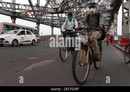 Un pendolari con l'ingranaggio protettivo cavalcano le loro biciclette oltre il ponte di Howrah di punto di riferimento sopra il fiume di Ganga sulla Giornata Mondiale della bicicletta il 02,2021 giugno.India ha segnalato 132.788 infezioni fresche del Covid-19 oggi, prendendo il caseload a 28.307.832. Con 3.207 nuovi decessi, il numero delle vittime è ora di 335.102, secondo MoHFW. L'India continua ad essere la seconda nazione più colpita. Il tasso di positività del test è sceso al 6,57%. Con 26.513 casi segnalati nelle ultime 24 ore, Tamil Nadu è leader nella lista degli stati. È seguita da Karnataka con 14.304 nuove infezioni. Maharashtra ha riportato 14.123 casi. Kerala 19 Foto Stock