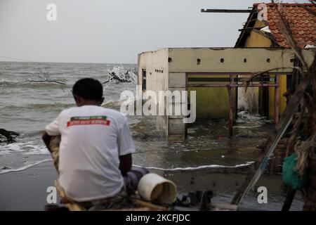 Rasali, seduto di fronte alla sua casa distrutta e annegata dall'abrasione delle onde marine nella costa settentrionale della città di Pekalonga, Giava Centrale, il 3 giugno 2021. Sulla base dei dati dell'Agenzia geologica del Ministero indonesiano dell'energia e delle risorse minerarie, la città di Pekalonga sta vivendo una subsidenza di terra di 6 centimetri all'anno, causata dall'uso massiccio delle acque sotterranee da parte dei tetti, dell'agricoltura, dell'industria e del cambiamento climatico globale, che, se non immediatamente mitigato, la città è prevista affondare nel 2036. (Foto di Aditya Irawan/NurPhoto) Foto Stock