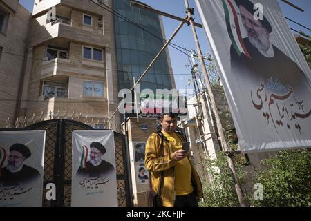 Un uomo iraniano usa il suo smartphone mentre si trova accanto alle bandiere elettorali per il politico conservatore, capo della magistratura iraniana, e il candidato iraniano alle elezioni presidenziali del 18 giugno Ebrahim Raisi, uscito da un centro di campagna elettorale nella parte occidentale di Teheran il 3 giugno 2021. (Foto di Morteza Nikoubazl/NurPhoto) Foto Stock