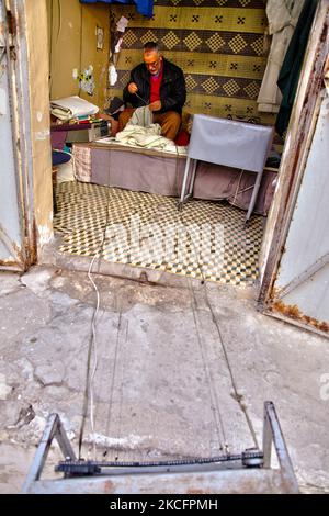 L'uomo usa un dispositivo per mantenere il filo di seta non aggrovigliato mentre cucita un indumento in un piccolo negozio nella medina (città vecchia) a Tangeri (Tangeri), Marocco, Africa. (Foto di Creative Touch Imaging Ltd./NurPhoto) Foto Stock