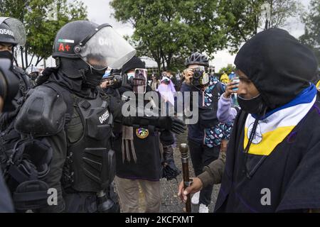 Gli indigeni di Misak si trovano di fronte ai poliziotti mentre protestano accanto alla statua della regina Isabel di Spagna il 09 giugno 2021 a Bogotà, Colombia. Un altro giorno di proteste a Bogotà Colombia, oggi in compagnia degli indigeni Misak che fingettero di abbattere la statua di ''Isabel il cattolico'' e Cristobal Colon conquistatore d'America. (Foto di David Rodriguez/NurPhoto) Foto Stock