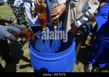 Gli ufficiali distruggono le bevande alcoliche confiscate per non utilizzare i francobolli di accisa in conformità alle normative dell'Ufficio di vigilanza e servizi doganali (KPPBC) TMP C Pantoloan a Palu, nella provincia di Sulawesi centrale, Indonesia, il 10 giugno 2021. Funzionari doganali e accise arrestati, confiscati e distrutti migliaia di bottiglie di bevande alcoliche e sigarette illegali perché hanno danneggiato le finanze del paese. (Foto di Mohamad Hamzah/NurPhoto) Foto Stock