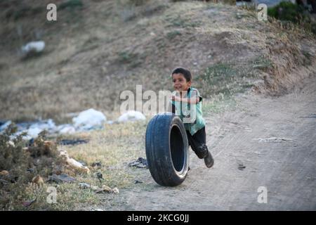 Bambini che giocano con vecchie gomme vicino ad un campo per gli sfollati vicino al villaggio di Nasiriyah al confine con la Turchia il 11 giugno 2021. (Foto di rami Alsayed/NurPhoto) Foto Stock