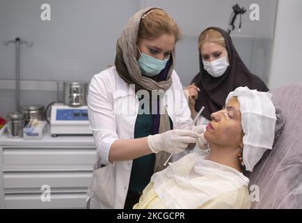 Il personale medico prepara Masoumeh Ataei, che è una vittima per l'operazione di ripristino dell'iniezione di grasso sotto la pelle del suo viso presso la clinica dermatologica Nilforooshzadeh nel nord di Teheran, il 19 giugno 2021. Dieci anni fa, un anno e mezzo dopo che Masoumeh Ataei ottenne il divorzio dal marito, perse il volto e la vista dopo un attacco acido da parte del suocero, ma dovette perdonarlo a causa di una ragione personale, Ora dopo dieci anni deve andare in Gran Bretagna e deve raccogliere 70.000 GBP per le spese di chirurgia se vuole riacquistare la vista. (Foto di Morteza Nikoubazl/N Foto Stock