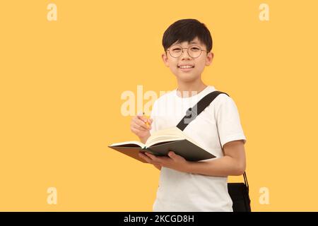 Uno studente con uno zaino e un libro sorride felicemente con un'espressione luminosa. Foto Stock