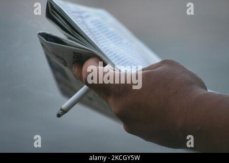 Uomo che tiene una sigaretta illuminata mentre legge un giornale nel centro di Toronto, Ontario, Canada. (Foto di Creative Touch Imaging Ltd./NurPhoto) Foto Stock