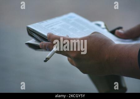 Uomo che tiene una sigaretta illuminata mentre legge un giornale nel centro di Toronto, Ontario, Canada. (Foto di Creative Touch Imaging Ltd./NurPhoto) Foto Stock