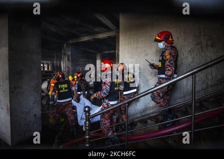 Vigili del fuoco e soccorritori trasportano i corpi che sono stati recuperati dopo uno scoppio di un incendio alla Hashem Foods Ltd a Rupganj, alla periferia di Dhaka, Bangladesh, 9 luglio 2021. Secondo i vigili del fuoco, almeno 52 persone sono morte dopo che questo incendio è scoppiato nella fabbrica. (Foto di Ahmed Salahuddin/NurPhoto) Foto Stock