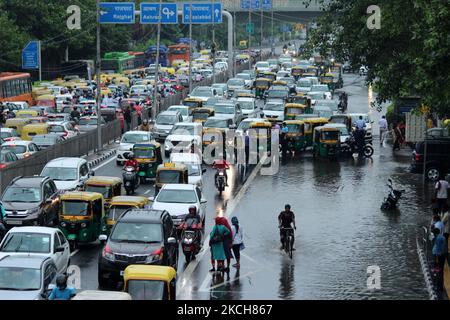 I pendolari aspettano i trasporti pubblici lungo una strada allagata dopo le forti piogge a Nuova Delhi, India, il 14 luglio 2021. La pioggia monsonica ha fornito un certo sollievo ai residenti dall'estate ardente ma anche causato il disboscamento dell'acqua e gli ingorghi del traffico in parecchie parti della capitale nazionale. (Foto di Mayank Makhija/NurPhoto) Foto Stock