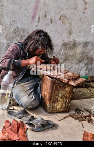 Metal worker utilizza uno scalpello per creare piccoli disegni in un foglio di rame in un workshop a Kathmandu City, Nepal, il 15 dicembre 2011. (Foto di Creative Touch Imaging Ltd./NurPhoto) Foto Stock