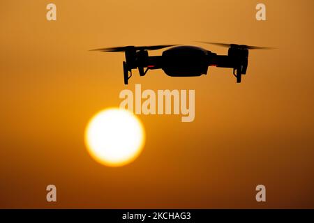 Un quadricottero che sorvola durante un volo di fronte al sole. Il drone volante è visto come una silhouette scura contro lo spettacolare cielo del tramonto colorato e il sole, mentre l'UAV è in grado di catturare la videografia aerea e la fotografia tramite un telecomando. Il drone specifico è un DJI Mavic Air. Il veicolo aereo senza equipaggio è popolare per l'uso ricreativo da parte dei turisti in quanto la tecnologia è accessibile a tutti a basso costo, ma ha anche molte applicazioni professionali sani Beach area, Halkidiki, Grecia il 15 luglio 2021 (Foto di Nicolas Economou/NurPhoto) Foto Stock