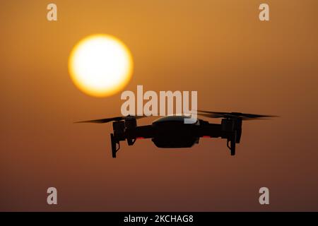 Un quadricottero che sorvola durante un volo di fronte al sole. Il drone volante è visto come una silhouette scura contro lo spettacolare cielo del tramonto colorato e il sole, mentre l'UAV è in grado di catturare la videografia aerea e la fotografia tramite un telecomando. Il drone specifico è un DJI Mavic Air. Il veicolo aereo senza equipaggio è popolare per l'uso ricreativo da parte dei turisti in quanto la tecnologia è accessibile a tutti a basso costo, ma ha anche molte applicazioni professionali sani Beach area, Halkidiki, Grecia il 15 luglio 2021 (Foto di Nicolas Economou/NurPhoto) Foto Stock