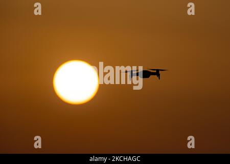 Un quadricottero che sorvola durante un volo di fronte al sole. Il drone volante è visto come una silhouette scura contro lo spettacolare cielo del tramonto colorato e il sole, mentre l'UAV è in grado di catturare la videografia aerea e la fotografia tramite un telecomando. Il drone specifico è un DJI Mavic Air. Il veicolo aereo senza equipaggio è popolare per l'uso ricreativo da parte dei turisti in quanto la tecnologia è accessibile a tutti a basso costo, ma ha anche molte applicazioni professionali sani Beach area, Halkidiki, Grecia il 15 luglio 2021 (Foto di Nicolas Economou/NurPhoto) Foto Stock