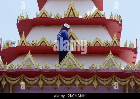 Un operaio dipinse su un tetto di cremazione durante il reinnovate in un tempio nella provincia di Nonthaburi, alla periferia di Bangkok il 17 luglio 2021. (Foto di Chaiwat Subprasom/NurPhoto) Foto Stock