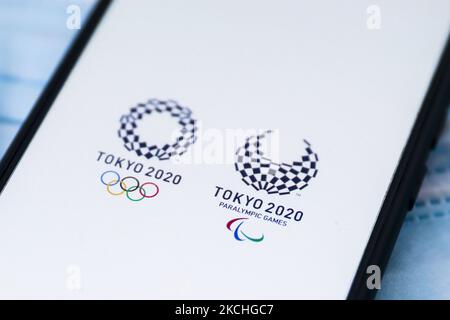 I logo delle Olimpiadi e dei Giochi Paralimpici di Tokyo 2020 sono visualizzati su uno schermo del telefono cellulare fotografato su uno sfondo di maschere chirurgiche per foto di illustrazione durante la pandemia di coronavirus. Cracovia, Polonia il 17 luglio 2021. (Foto di Beata Zawrzel/NurPhoto) Foto Stock