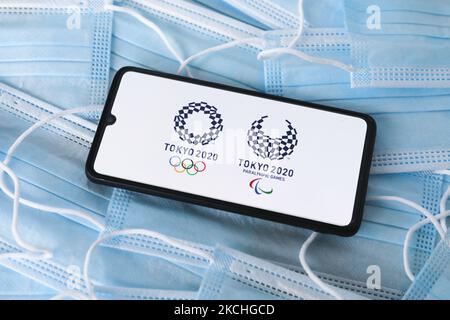 I logo delle Olimpiadi e dei Giochi Paralimpici di Tokyo 2020 sono visualizzati su uno schermo del telefono cellulare fotografato su uno sfondo di maschere chirurgiche per foto di illustrazione durante la pandemia di coronavirus. Cracovia, Polonia il 17 luglio 2021. (Foto di Beata Zawrzel/NurPhoto) Foto Stock