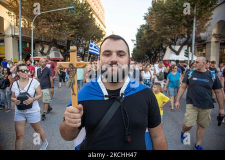 Un giovane manifestante maschile sta tenendo una croce con Gesù e portando la bandiera greca durante la dimostrazione contro il vaccino obbligatorio si è tenuta a Salonicco e ad Atene in Grecia mercoledì 21 luglio 2021. Una settimana dopo la massiccia protesta contro la vaccinazione obbligatoria, la campagna anti-vaxx continua con un grande gruppo che protesta nelle strade della città di Salonicco. La protesta è stata organizzata attraverso i social media da credenti anti-vaccinazioni. Secondo il gruppo hanno partecipato più di 40,000 persone, mentre la polizia ha valutato ufficiosamente circa 15,000 persone participati Foto Stock