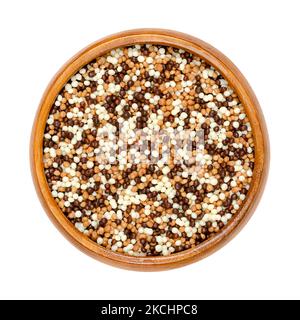 Mini mix di perle croccanti al cioccolato, in una ciotola di legno. Estruso di cereali croccanti dolci con rivestimento di cioccolato fondente, latte e bianco. Decorazione. Foto Stock