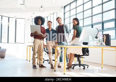 Bene sia la vostra squadra di sogno di disegno. Ritratto di un team di designer felici che lavorano su una scrivania nel loro ufficio moderno. Foto Stock
