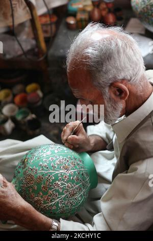 Un artigiano Kashmiri di 78 anni dipinge un disegno intricato su un vaso di carta in un laboratorio galleggiante lungo dal Lake a Srinagar, Kashmir, India, il 26 giugno 2010. (Foto di Creative Touch Imaging Ltd./NurPhoto) Foto Stock