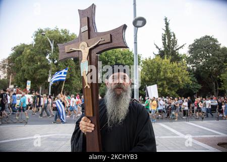 Un sacerdote porta una croce con Gesù durante la manifestazione. Centinaia di persone, meno del grande raduno precedente, si vedono alla dimostrazione contro il vaccino obbligatorio che si è tenuta a Salonicco in Grecia mercoledì 28 luglio 2021. Una settimana dopo la massiccia protesta contro la vaccinazione obbligatoria, la campagna anti-vaxx continua con un grande gruppo che protesta nelle strade della città di Salonicco. La protesta è stata organizzata attraverso i social media da credenti anti-vaccinazioni. Secondo il gruppo hanno partecipato più di 5000 persone, mentre la polizia ha stimato che non ufficialmente scivola Foto Stock